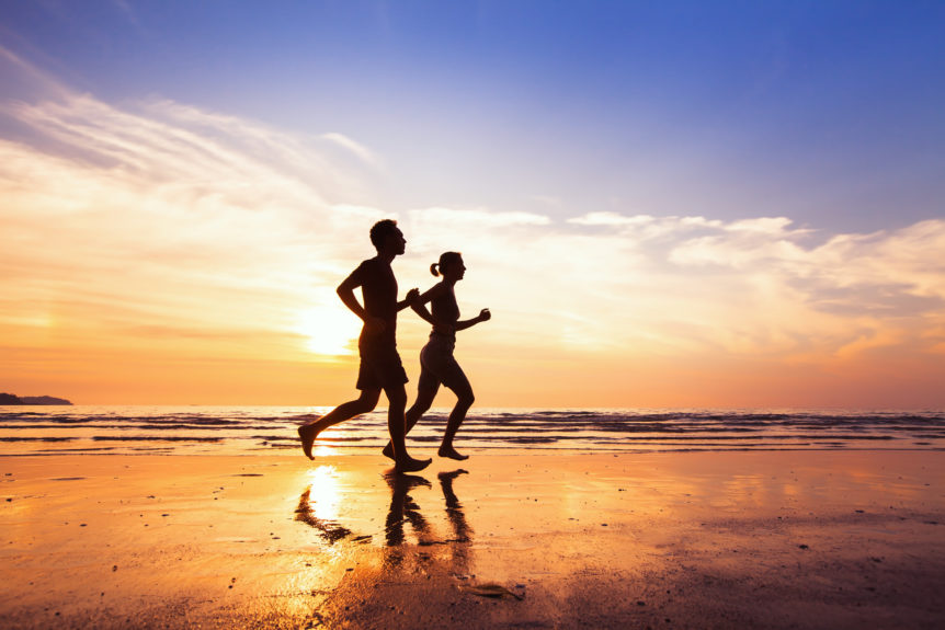 sport and healthy lifestyle, two people jogging at sunset on the beach